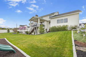 Back of house featuring fence, stairs, a chimney, stucco siding, and a yard