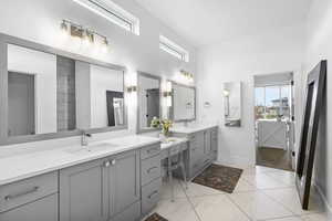 Full bathroom with baseboards, two vanities, a towering ceiling, and a sink