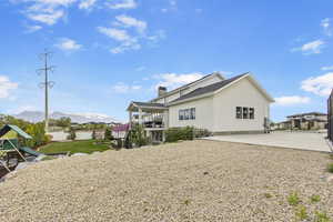 Back of property with fence, a playground, a chimney, a mountain view, and stucco siding