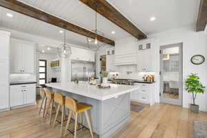 Kitchen with white cabinets, stainless steel appliances, a kitchen bar, light wood-type flooring, and backsplash