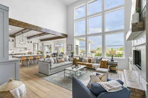 Living area with a premium fireplace, a healthy amount of sunlight, a high ceiling, and wood-type flooring