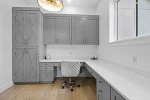 Office space featuring baseboards, light wood-type flooring, and built in study area
