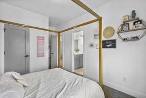 Bedroom with baseboards, ensuite bath, carpet floors, and a closet