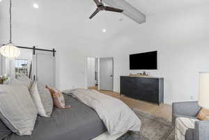 Bedroom with beamed ceiling, recessed lighting, a barn door, light wood-style floors, and high vaulted ceiling