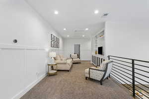 Carpeted living area with recessed lighting, a wainscoted wall, visible vents, and a decorative wall