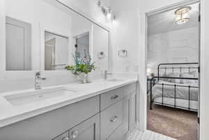 Full bathroom with double vanity, a shower stall, ensuite bathroom, and a sink