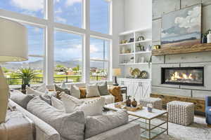 Living room with a wealth of natural light, a glass covered fireplace, a mountain view, and a high ceiling