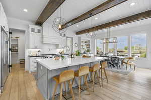 Kitchen with glass insert cabinets, a breakfast bar area, decorative backsplash, and light wood-style floors