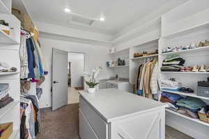 Walk in closet featuring attic access, carpet flooring, and independent washer and dryer