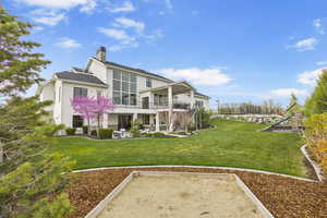 Rear view of house with stairs, a chimney, a patio area, a lawn, and stucco siding