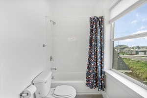 Bathroom featuring tile patterned floors, shower / bath combo, and toilet