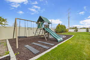 Community jungle gym with a fenced backyard and a lawn