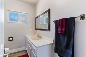 Bathroom featuring baseboards, wood finished floors, a wealth of natural light, and vanity