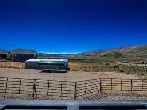 View of patio / terrace featuring an outdoor structure, a mountain view, an enclosed area, and a rural view