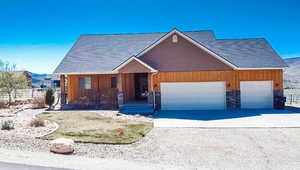 View of front of house featuring concrete driveway, stone siding, an attached garage, and fence