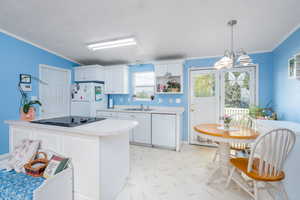 Kitchen featuring crown molding, white cabinets, a sink, light countertops, and white appliances