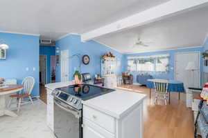 Kitchen with white cabinetry, crown molding, stainless steel electric stove, visible vents, and light wood-style floors