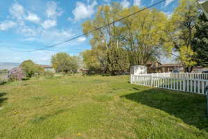 View of yard featuring a storage unit, fence, and an outbuilding
