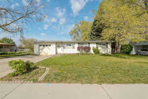 Ranch-style home with a front yard, concrete driveway, and an attached garage