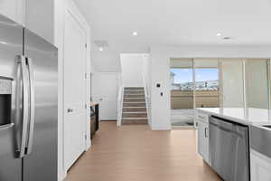 Kitchen featuring recessed lighting, stainless steel appliances, light wood-type flooring, light countertops, and white cabinets