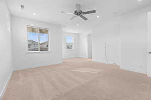 Empty room featuring baseboards, visible vents, light carpet, and ceiling fan