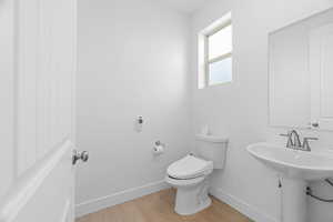 Bathroom featuring wood finished floors, toilet, and baseboards