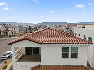 Back of house with stucco siding, a mountain view, a residential view, and a tile roof