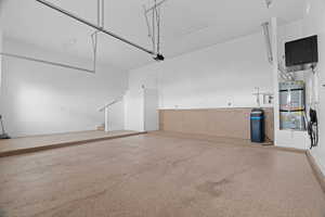 Garage with a garage door opener, water heater, and electric panel