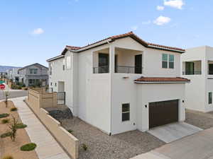 View of back facade featuring a tile roof, concrete driveway, a garage, and fence
