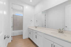 Full bathroom featuring double vanity, wood finished floors, recessed lighting, and a sink
