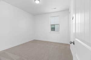 Empty room with baseboards, visible vents, and light carpet