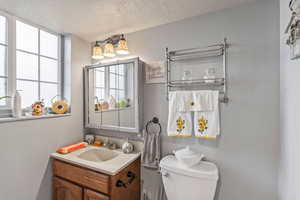 Bathroom with a textured ceiling, vanity, and toilet