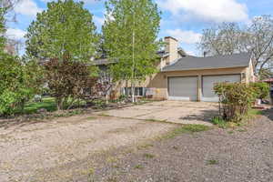 View of front of home with a chimney, brick siding, a garage, roof with shingles, and concrete driveway