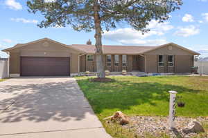 Ranch-style home with concrete driveway, a front lawn, an attached garage, and brick siding