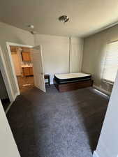 Unfurnished bedroom featuring baseboards, dark carpet, and a textured ceiling