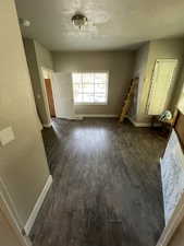 Interior space with a textured ceiling, dark wood finished floors, and baseboards