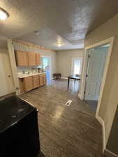Kitchen featuring dark wood-style floors, black / electric stove, visible vents, baseboards, and a textured ceiling