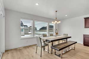 Dining area with light wood finished floors, an inviting chandelier, baseboards, and recessed lighting