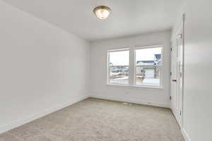 Empty room with light colored carpet, baseboards, and visible vents