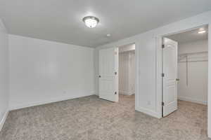 Unfurnished bedroom featuring a closet, baseboards, a spacious closet, a textured ceiling, and carpet floors