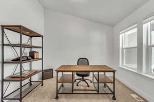 Home office with visible vents, baseboards, and light carpet
