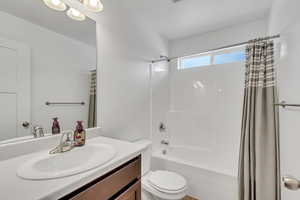 Full bathroom with toilet, shower / tub combo with curtain, and vanity