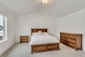 Bedroom featuring light carpet and lofted ceiling