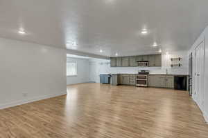Kitchen featuring open shelves, a sink, light wood-type flooring, gray cabinetry, and stainless steel appliances