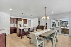Dining area featuring light wood-style floors, a notable chandelier, and recessed lighting