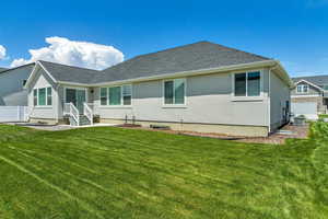 Rear view of property with central AC, a yard, fence, stucco siding, and roof with shingles
