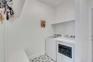 Laundry area with light tile patterned floors, separate washer and dryer, laundry area, and baseboards