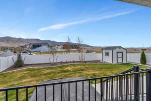 View of yard featuring an outdoor structure, a fenced backyard, a residential view, a mountain view, and a shed