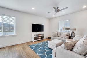 Living room with visible vents, ceiling fan, baseboards, and plenty of natural light