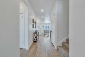 Corridor with baseboards, stairway, light wood-style flooring, and recessed lighting